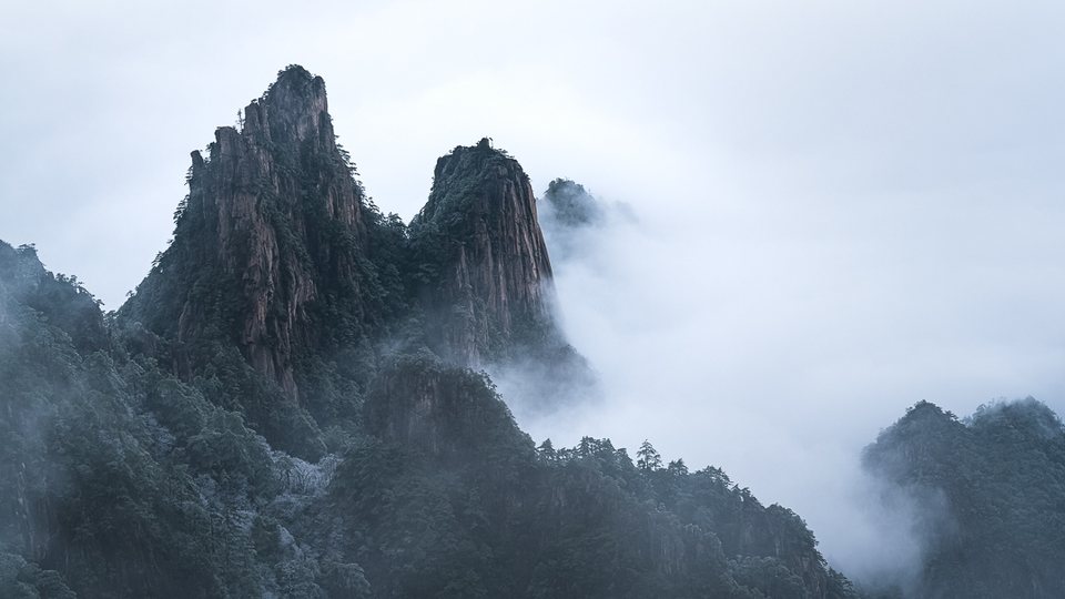 Misty mountain landscape with trees and low cloud